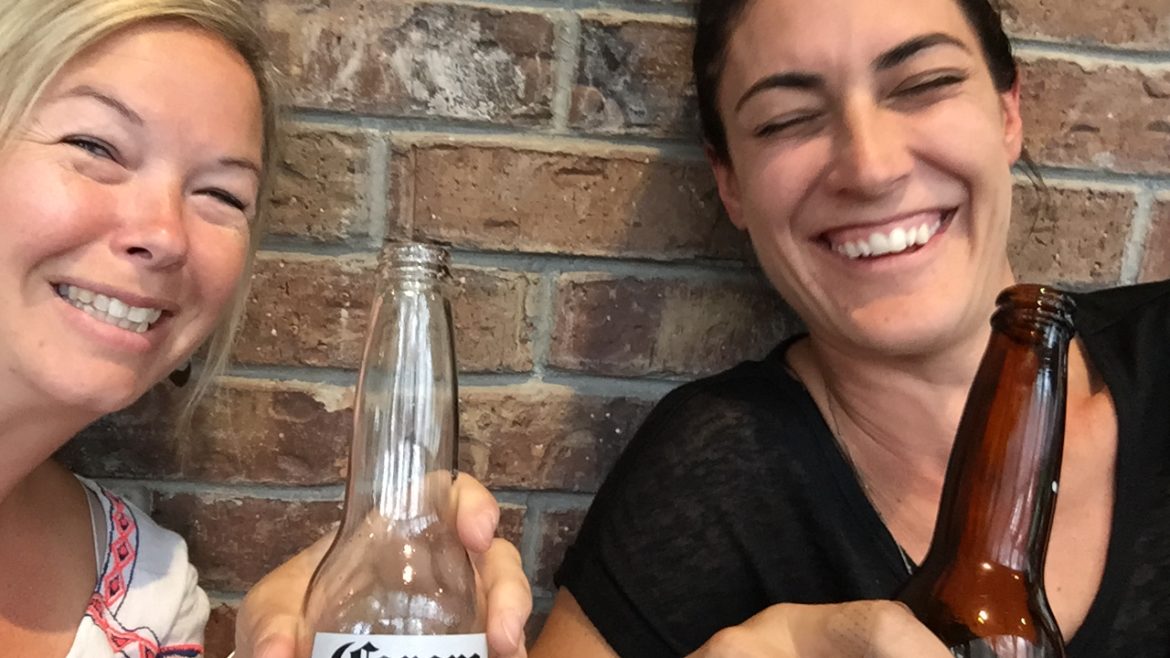 Photo of 2 girls drinking a beer together.