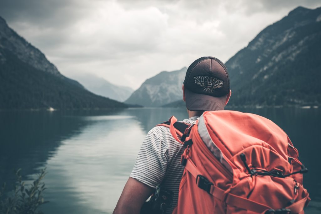 Photo of a dude wearing a backpack looking over a lake