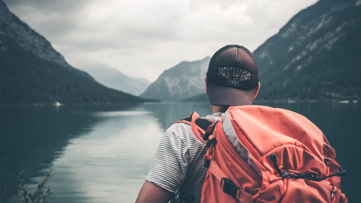 Photo of a dude wearing a backpack looking over a lake
